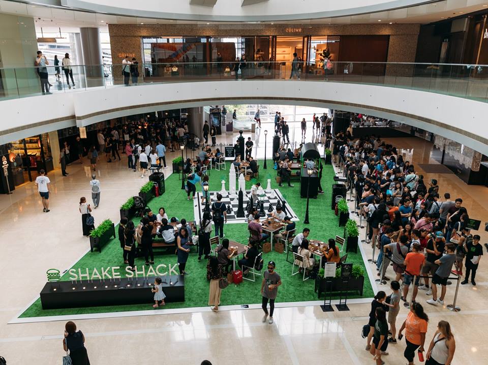 The pop-up from the balcony: life-sized chess, park benches and turf dropped into the middle of the mall, with the queue running down the right