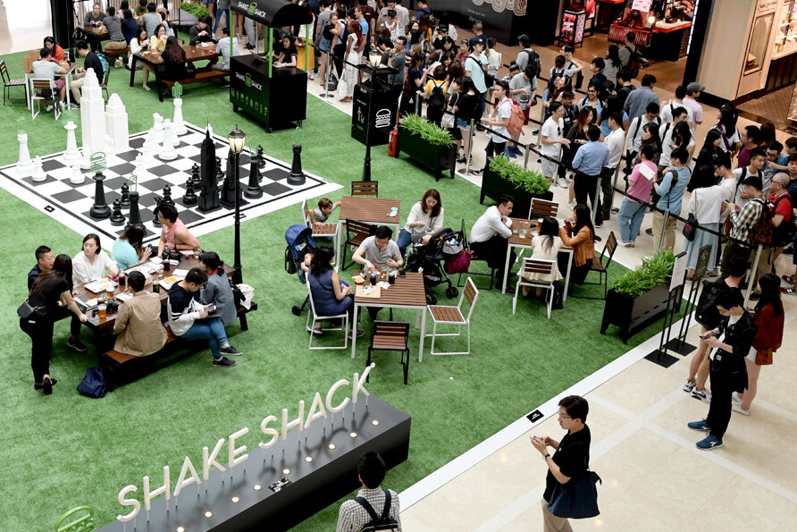 Closer in. People eating at picnic tables on turf, which is the Madison Square Park idea rather than the New York skyline one