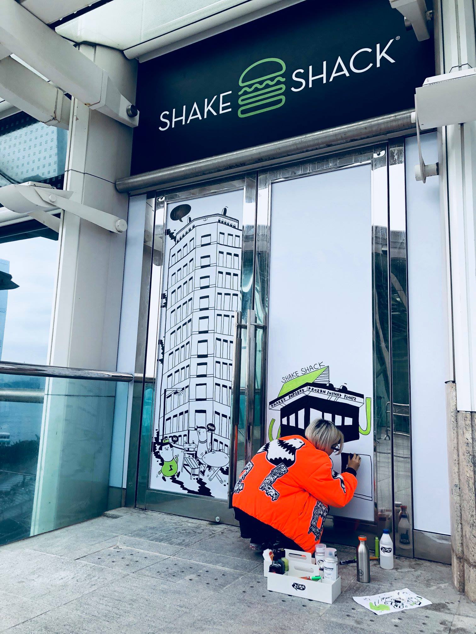 A local artist drawing the IFC storefront by hand before opening, putting the campaign's street art onto the building itself