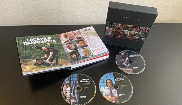 The screener package: slipcase, printed book and disc faces. Hand-held is the one place in the campaign where the type can get small and the image can breathe
